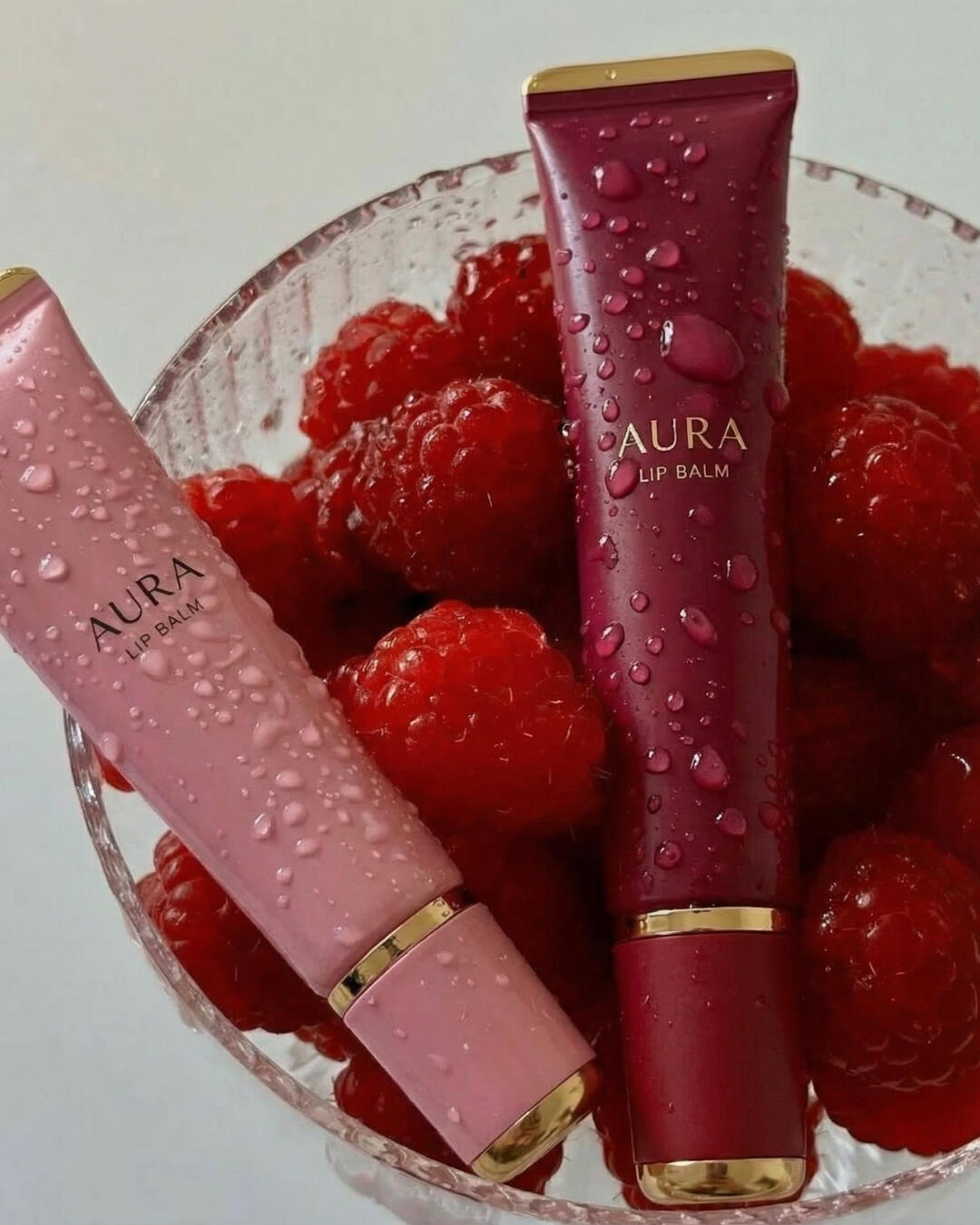 Untitled Commercial cosmetic product photography concept for a lip balm brand, contrasting a water-droplet texture on fresh raspberries.
