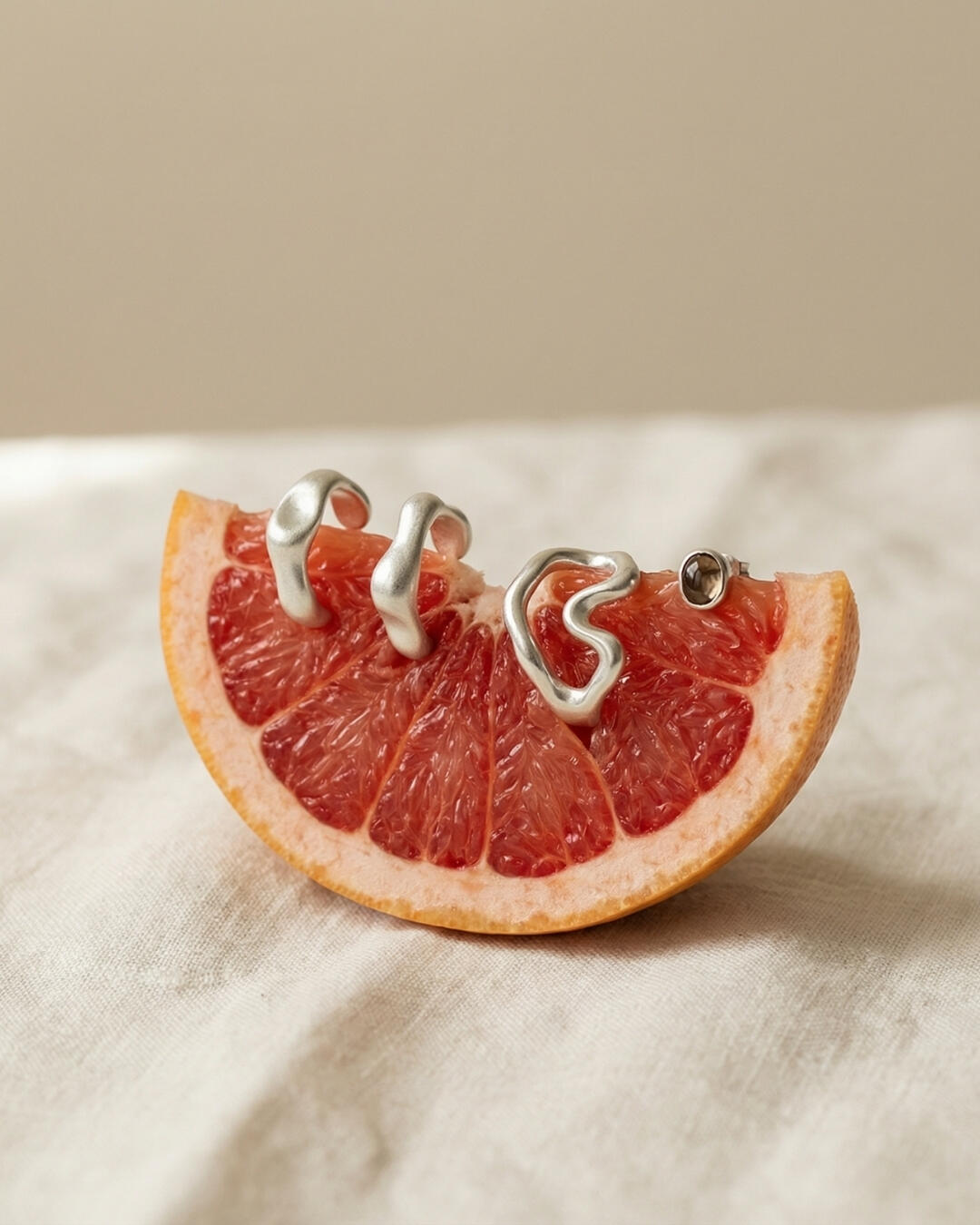 Untitled Diptych product photography display for a minimalist jewelry brand, styling silver rings on a fresh grapefruit slice.